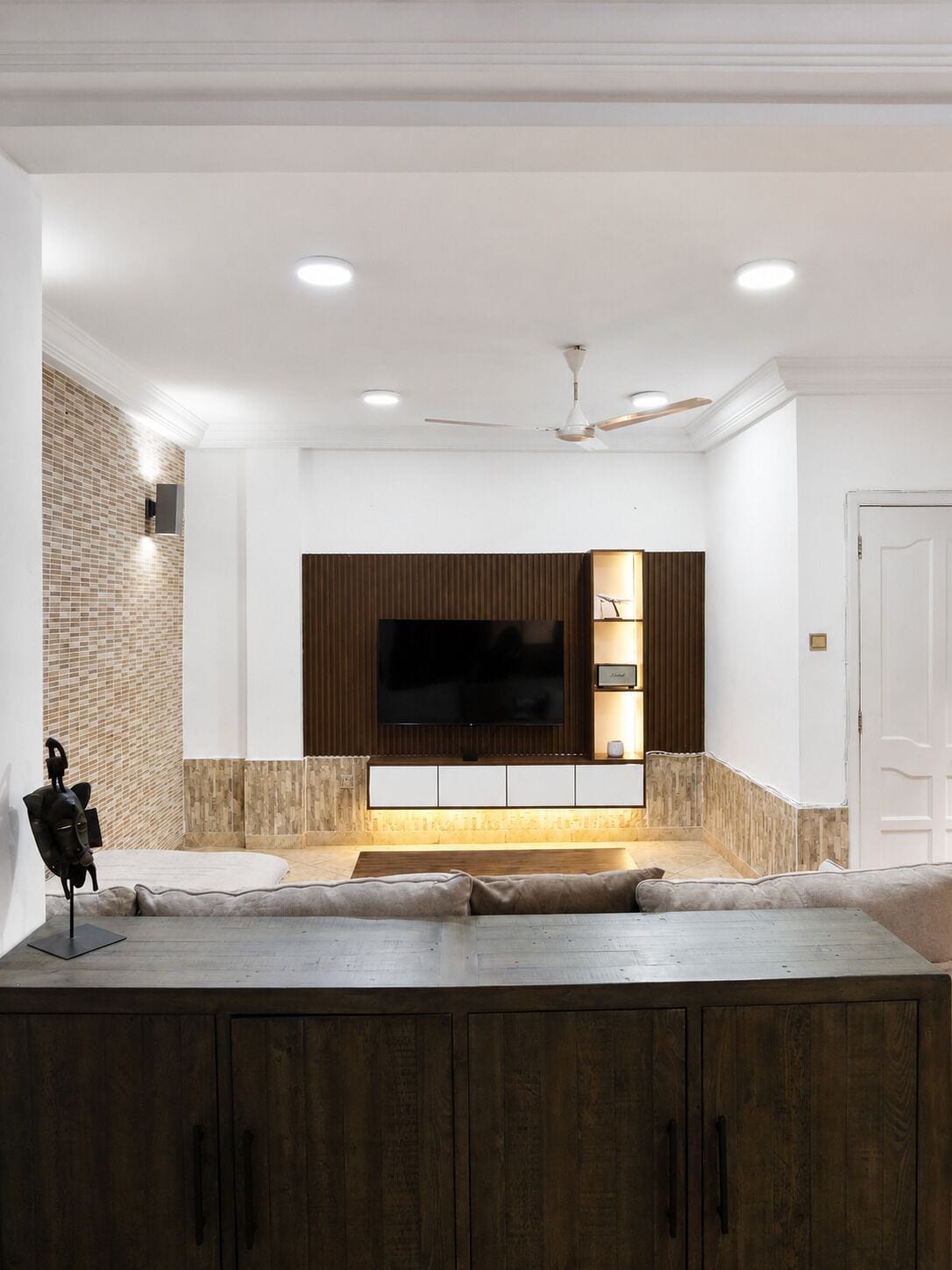 Un salon moderne doté d’un téléviseur à écran plat, de meubles en bois et d’un mur décoratif en briques.