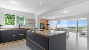 A modern kitchen with a central island, large windows, and a view of the outdoors. - Villa Azita is a spectacular Luxury Villa in Altea Hills, Panoramic Sea Views (Altea)