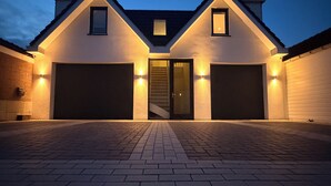 A two-story house with a central staircase, two garage doors, and exterior lighting. - Breeze Inn - Ibiza apartment, BioScience Park Leiden, beach, Leiden, (Oegstgeest)