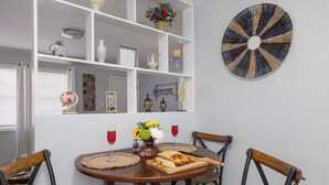 A dining area with a round wooden table, four wooden chairs, a white shelf with decorative items, and a wall-mounted circular art piece. - 2 Homes, Hot Tub,2 Kitchen, Nintendo, Big Parking (Lincolnton)