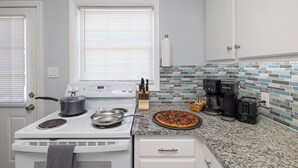 A kitchen with a stove, a pizza, a coffee maker, and a knife block. - 2 Homes, Hot Tub,2 Kitchen, Nintendo, Big Parking (Lincolnton)