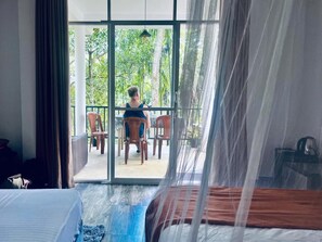 A room with a bed, a table with chairs, and a view of greenery outside. - Mithun Homestay (Ella)