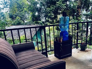 A balcony with a black metal railing, a blue water dispenser, and potted plants. - Mithun Homestay (Ella)