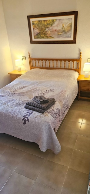Un lit bien fait, recouvert d’une couvre-lit à motifs floraux, avec deux lampes de chevet, une œuvre d’art encadr ée accrochée au mur et une tête de lit en bois.