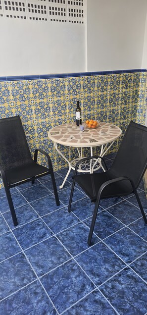A small outdoor seating area with a round table and two chairs, a bottle, and a bowl of oranges. - Holiday Home 'Marolesja' with Mountain View, Wi-Fi and Air Conditioning (Puerto de Mazarrón)