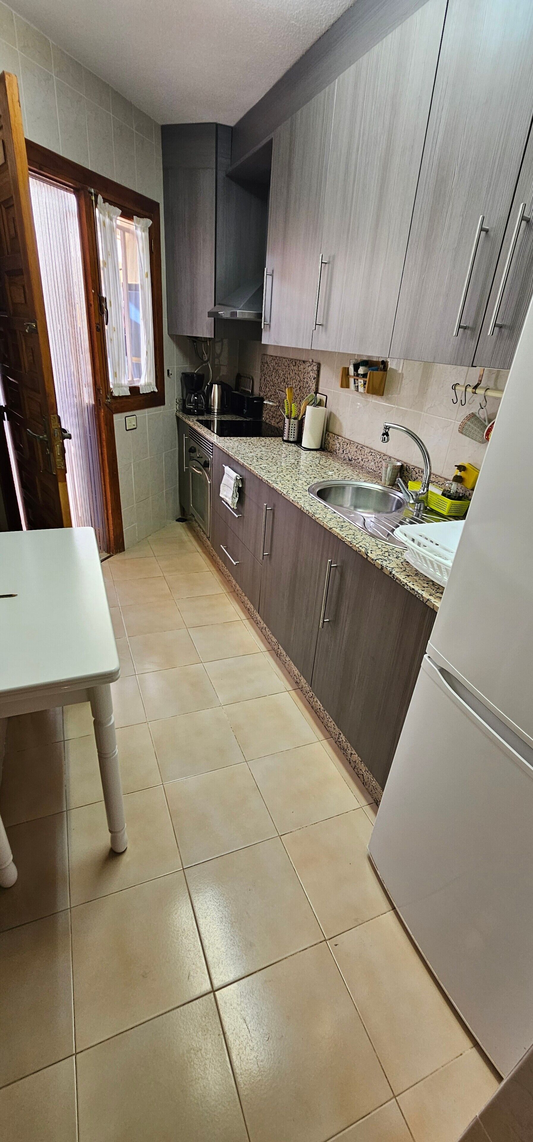 Una cocina compacta con lavamanos, estufa y refrigerador.