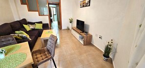 Un salon avec un canapé, une table à manger, un téléviseur et une plante en pot.