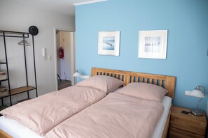 Un letto matrimoniale con testiera in legno, un comodino con una lampada e due quadri appesi al muro.