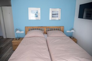 Un letto matrimoniale con testiera in legno, due comodini con lampade e due quadri appesi al muro.
