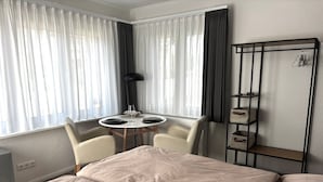 A hotel room with a bed, a small table with chairs, a radiator, and a shelf with storage boxes. - studio no. 2 newly furnished, modern vacation in Wöhrden near Büsum (Wöhrden)