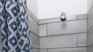 Une douche avec des carreaux gris et un pommeau de douche.