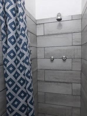 A shower with grey tiles and a showerhead. - Leaf & Lark (Bloemfontein)