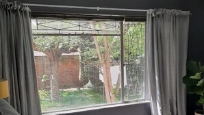 Un lit donnant sur un arbre visible par la fenêtre.