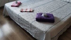 Un lit bien fait, avec une couvre-lit à motifs, un oreiller et deux serviettes pliées.