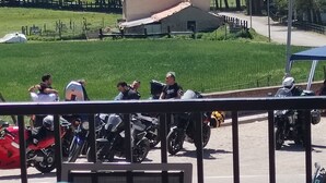 Un balcón con mesa y sillas, con vista a un estacionamiento con motocicletas.
