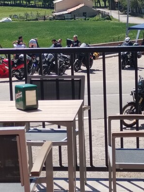 Ein Balkon mit Tisch und Stühlen, mit Blick auf einen Parkplatz mit Motorrädern.