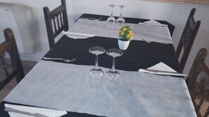 Una mesa de comedor dispuesta con copas de vino, un florero con flores amarillas y un mantel negro.