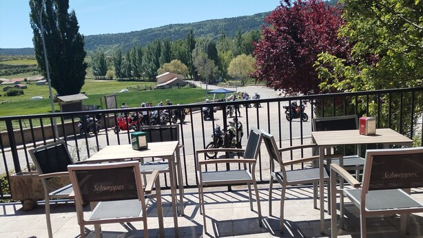 Un espace extérieur aménagé avec des tables et des chaises, une vue sur la campagne et un bâtiment situé au loin.
