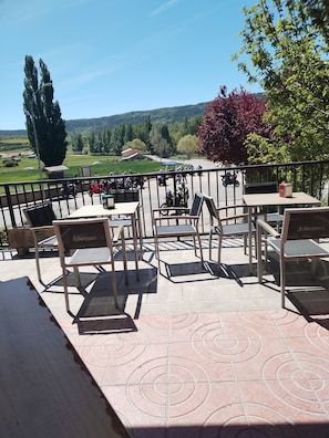 An outdoor seating area with tables and chairs, a view of the countryside, and a distant building. - hostal frias de albarracin (Frias de Albarracin)