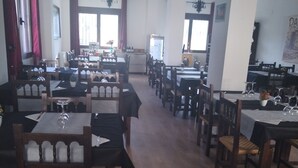 Un restaurant spacieux, doté de nombreuses tables et chaises, d’un comptoir central et d’appliques murales décoratives.