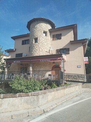 Ein Gebäude mit einem Steinturm, einer Bar namens 'Estrella Damm' und Außenbereich.