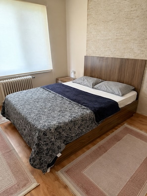 A bedroom with a bed, a nightstand, a lamp, a radiator, and a brick-patterned wall. - Kadıoğlu otel (Bursa)
