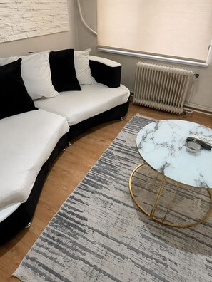 A modern living room with a sectional sofa, a marble coffee table, and a radiator. - Kadıoğlu otel (Bursa)