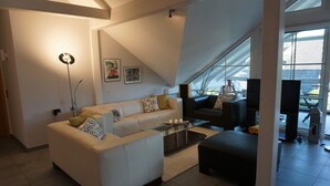 Ein modernes Wohnzimmer mit einer Couch, einem Couchtisch und einem Fernseher.