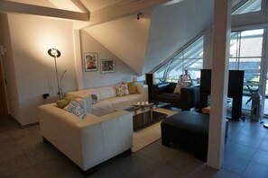 A modern living room with a sofa, coffee table, and a television. - Vacation apartment with conservatory, in a quiet location with outdoor seating for 4 pers. (Dürrwangen)
