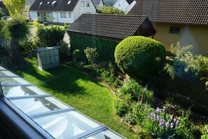 A residential garden with a well-maintained lawn, a variety of plants, and a small shed. - Vacation apartment with conservatory, in a quiet location with outdoor seating for 4 pers. (Dürrwangen)