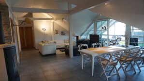 Ein modernes Interieur mit Essbereich, weißen Möbeln und großen Fenstern.
