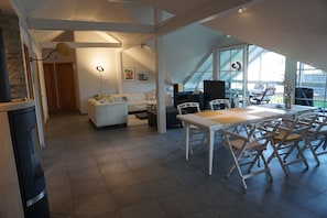A modern interior with a dining area, white furniture, and large windows. - Vacation apartment with conservatory, in a quiet location with outdoor seating for 4 pers. (Dürrwangen)