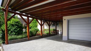 Ein überdachter Außenbereich mit Garage, Holzbalken und befestigtem Boden.