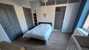 Makuuhuone, jossa on sänky, valkoinen pinnasänky, ovi, kirjahylly ja patteri.
