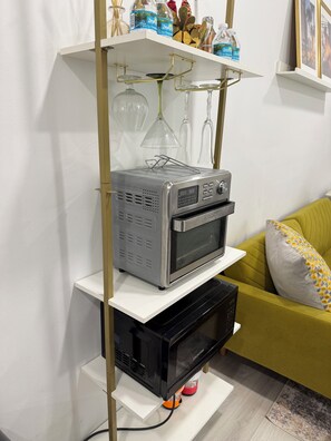 A kitchen with a microwave, toaster, and shelves with kitchenware. - Modern Tiny House in conveniently located Tampa Neighborhood. (Tampa)