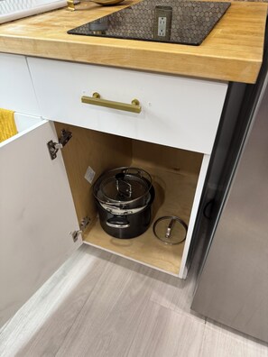 A kitchen with a wooden countertop, a white cabinet with a gold handle, and a stainless steel appliance. - Modern Tiny House in conveniently located Tampa Neighborhood. (Tampa)