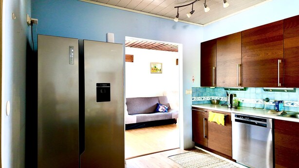 Eine Küche mit Kühlschrank, Holzschränken, Spüle und Arbeitsplatte.