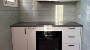 Eine Küche mit weißen Schränken, einem eingebauten Backofen und einem Fenster.
