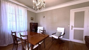 Ein Esszimmer mit Holztisch, Stühlen, einer Chandelierleuchtre und einer Tür.
