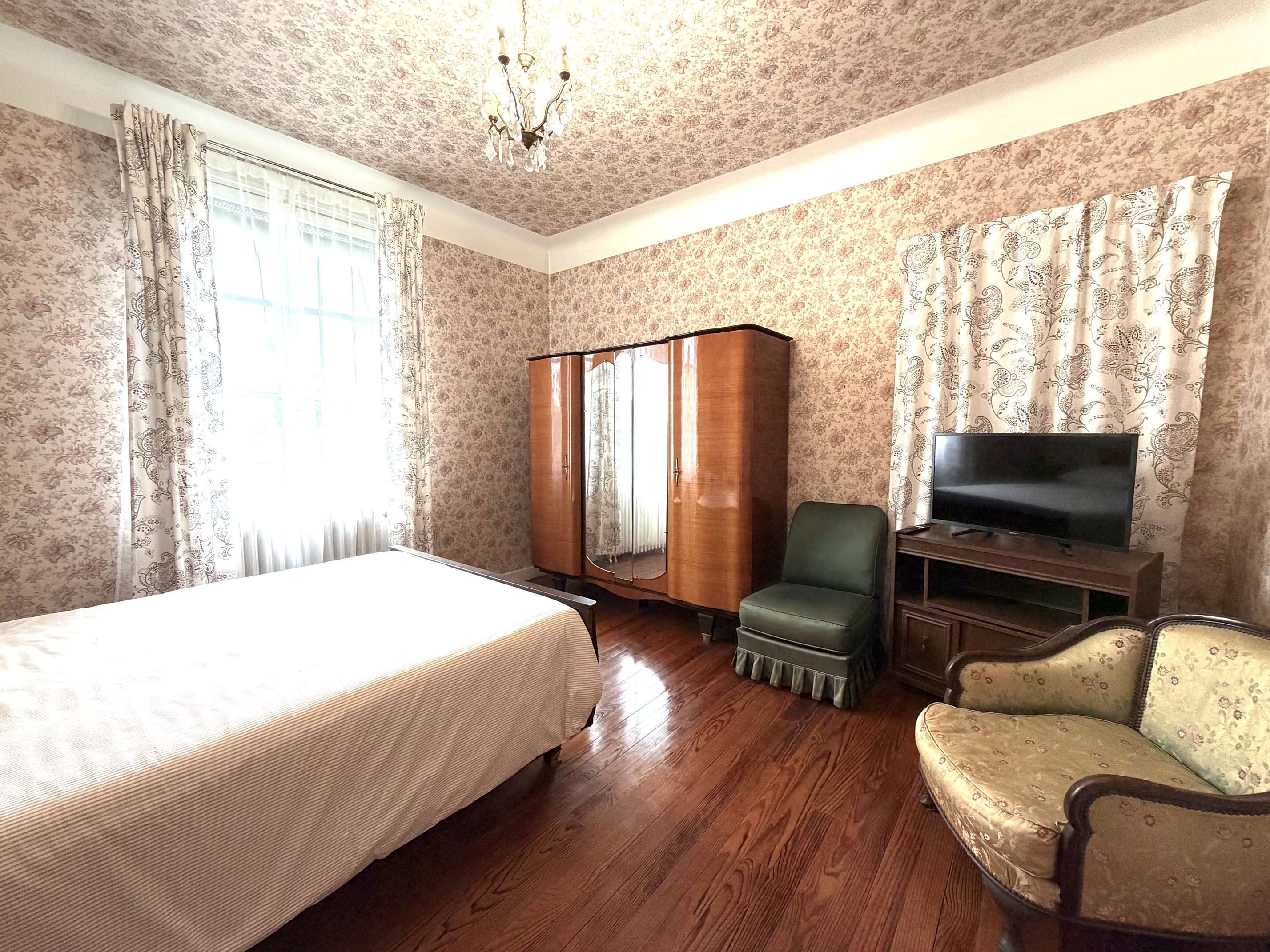 A hotel room with a bed, a wardrobe, a television, and a chair.