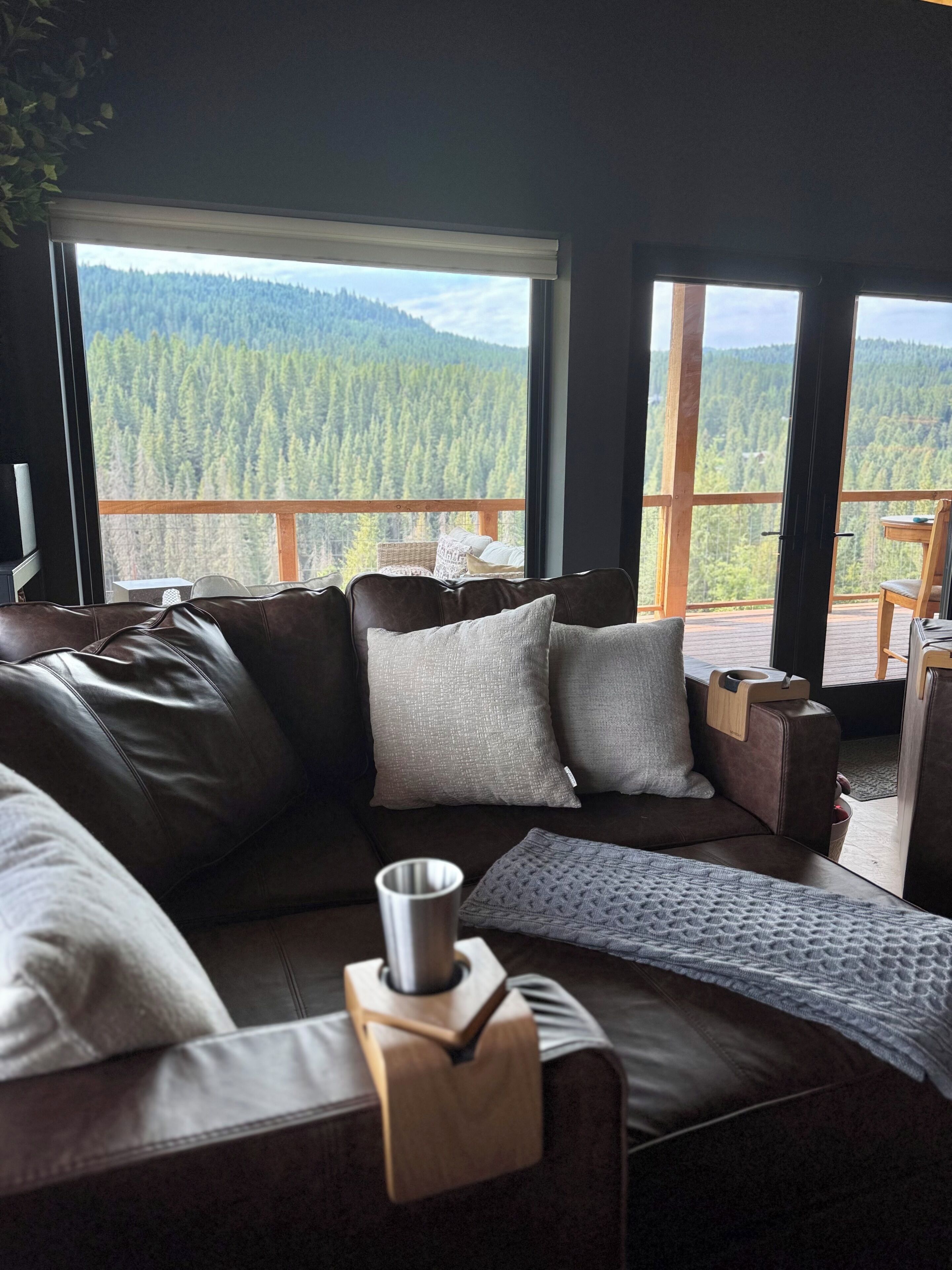 Een moderne woonkamer met een groot raam met uitzicht op een bebost berglandschap.