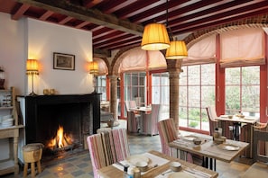 Una habitación acogedora con chimenea, sillas a rayas y una mesa lista para cenar.