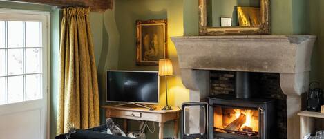 A cozy room with a fireplace, a chandelier, a bed, and a television.