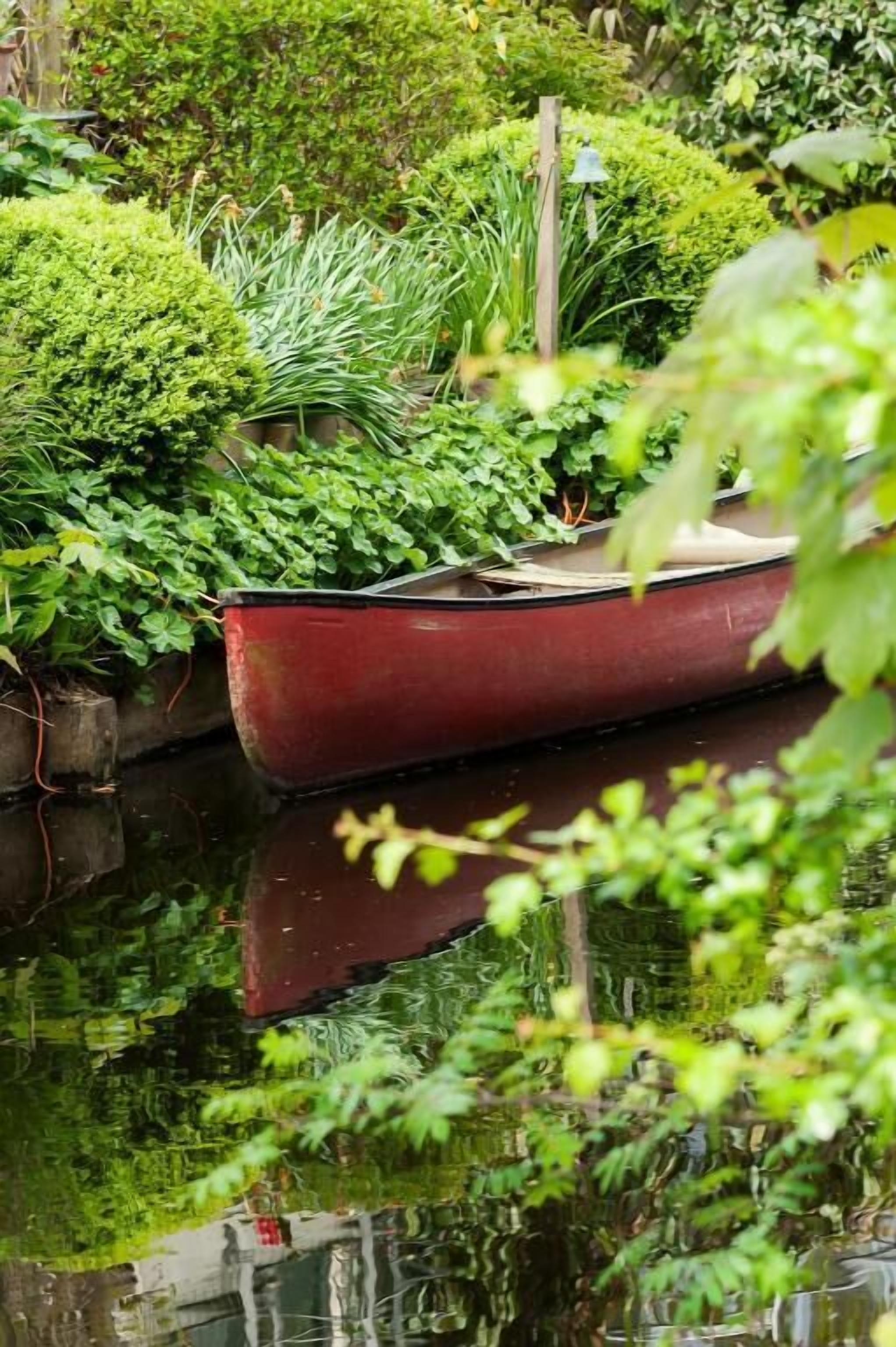 Un bateau rouge était amarré dans une étendue d’eau calme, entourée d’une végétation luxuriante.