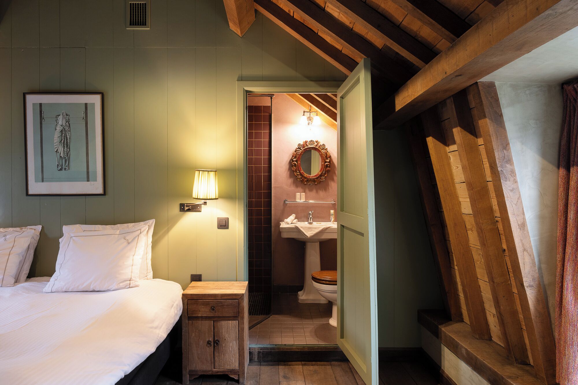 A bedroom with a bed, bedside table, lamp, and a framed picture on the wall.
