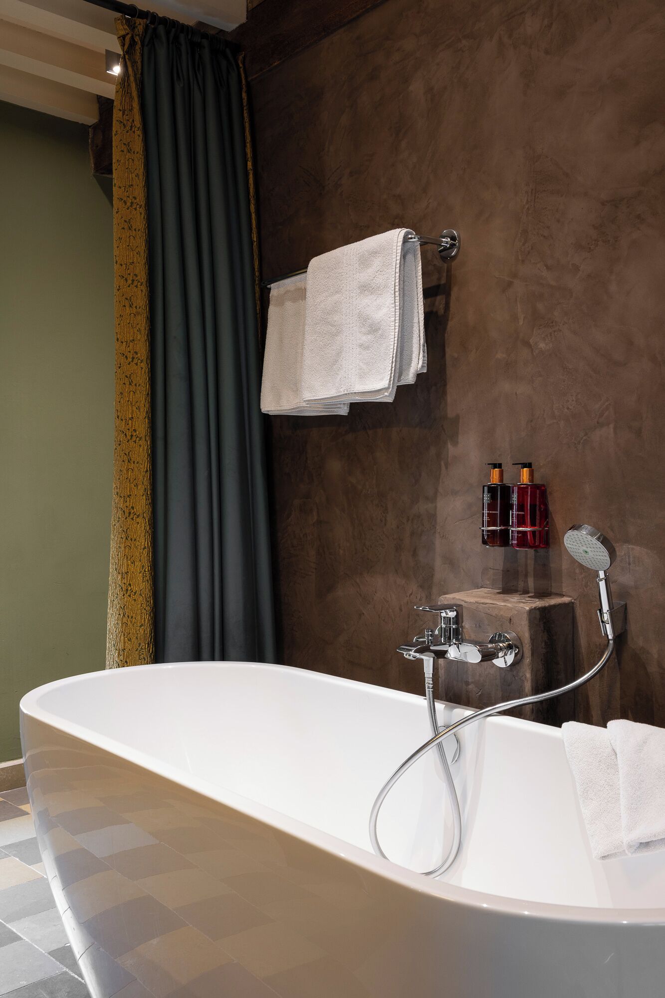 Une salle de bain moderne avec une baignoire sur pieds, un porte-serviettes et deux bouteilles de shampoing.