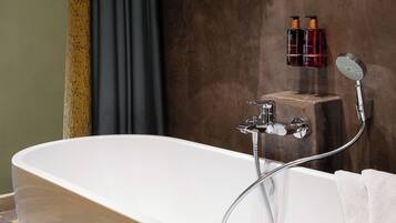Une salle de bain moderne avec une baignoire sur pieds, un porte-serviettes et deux bouteilles de shampoing.
