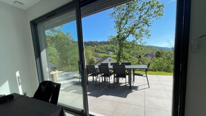 Ein Zimmer mit einer großen Schiebetür und Zugang zu einer Terrasse mit Tisch und Stühlen.