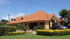 Una casa a due piani con tetto in tegole rosse, un portico e un giardino curato.