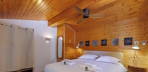 Ein Zimmer mit Holzwandverkleidung, einem Bett, einem Deckenventilator, einer Dusche und Wandleuchten.